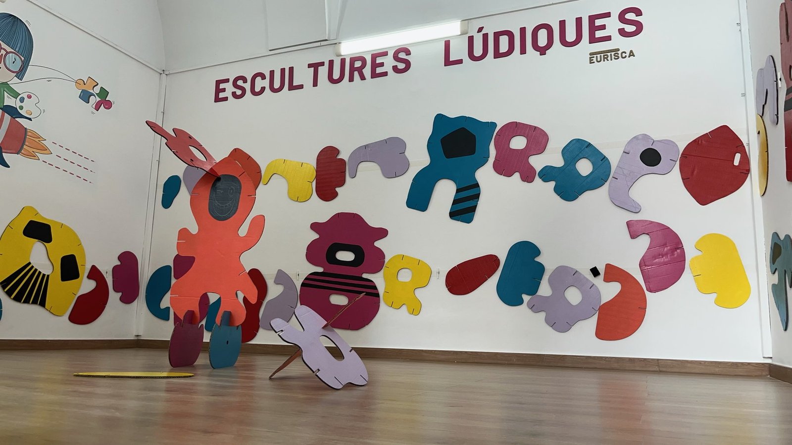 Sala de Escultures Lúdiques con piezas de cartón de colores dispuestas en paredes y suelo.