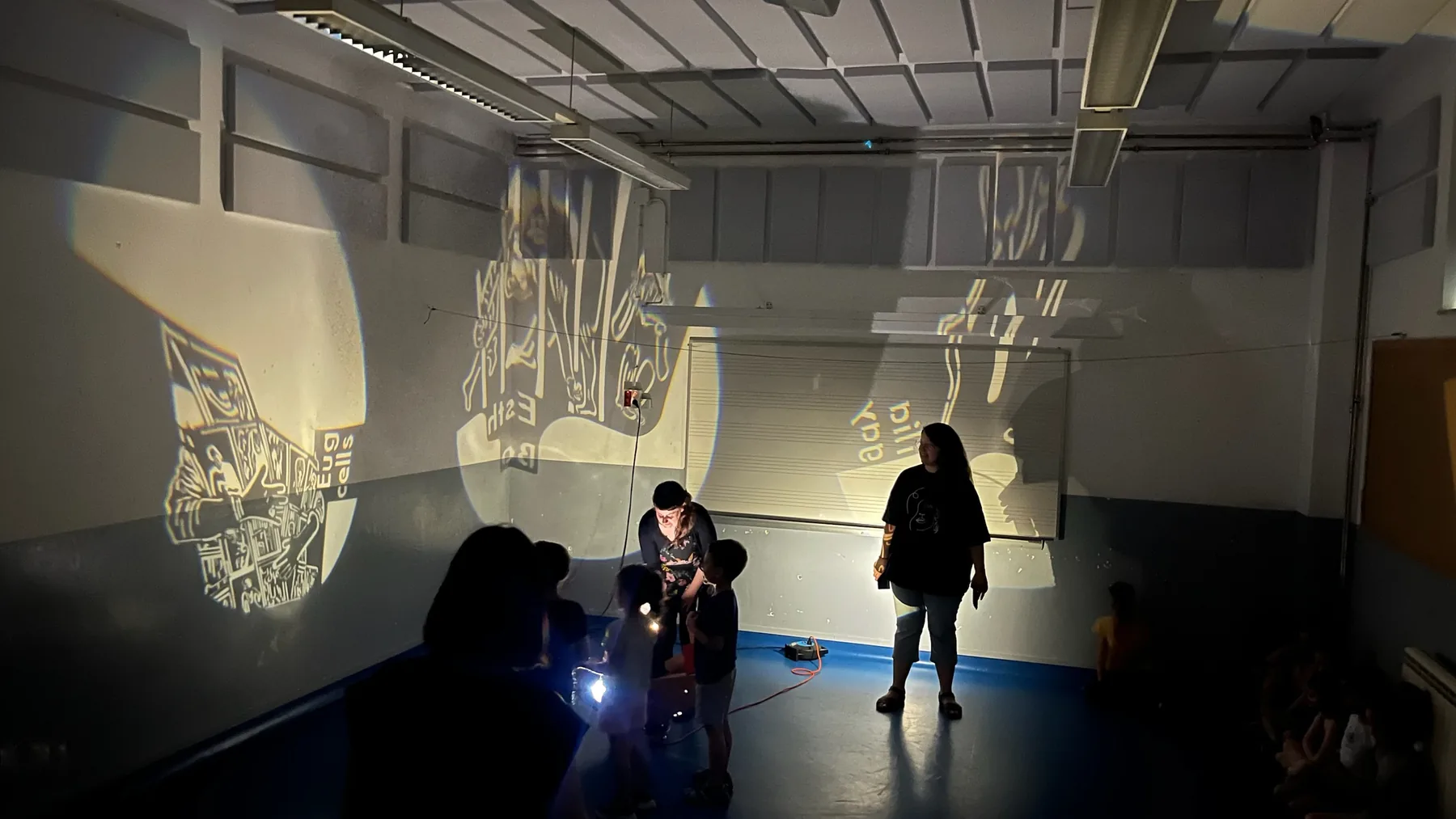 Personas participando en una sala cubierta por proyecciones gráficas de Pioneres.