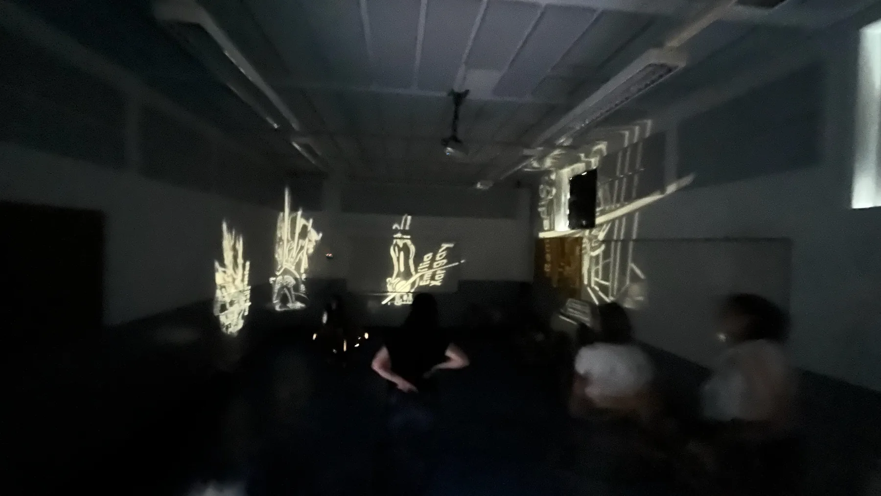 Grupo dentro de una sala oscura con proyecciones de Pioneres en varias paredes.