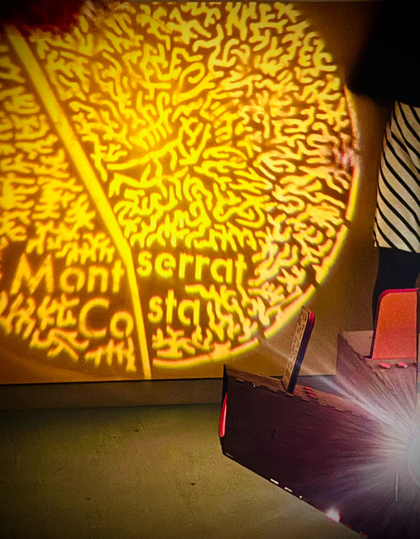 Detalle de palabras y formas luminosas proyectadas sobre una superficie.