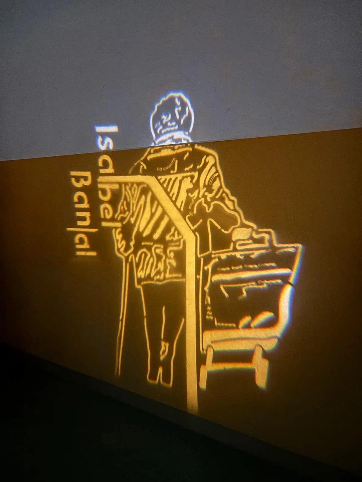 Proyección luminosa de una figura y palabras vinculadas a una artista.