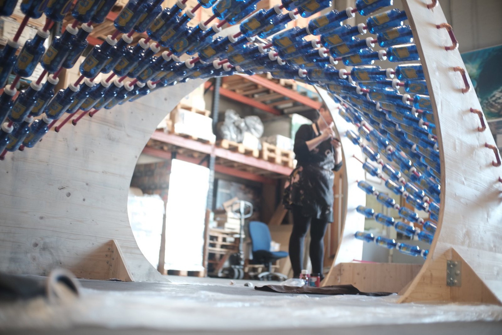 Vista desde el interior de la estructura ondulada de REFLEX y sus hileras de botellas azules.